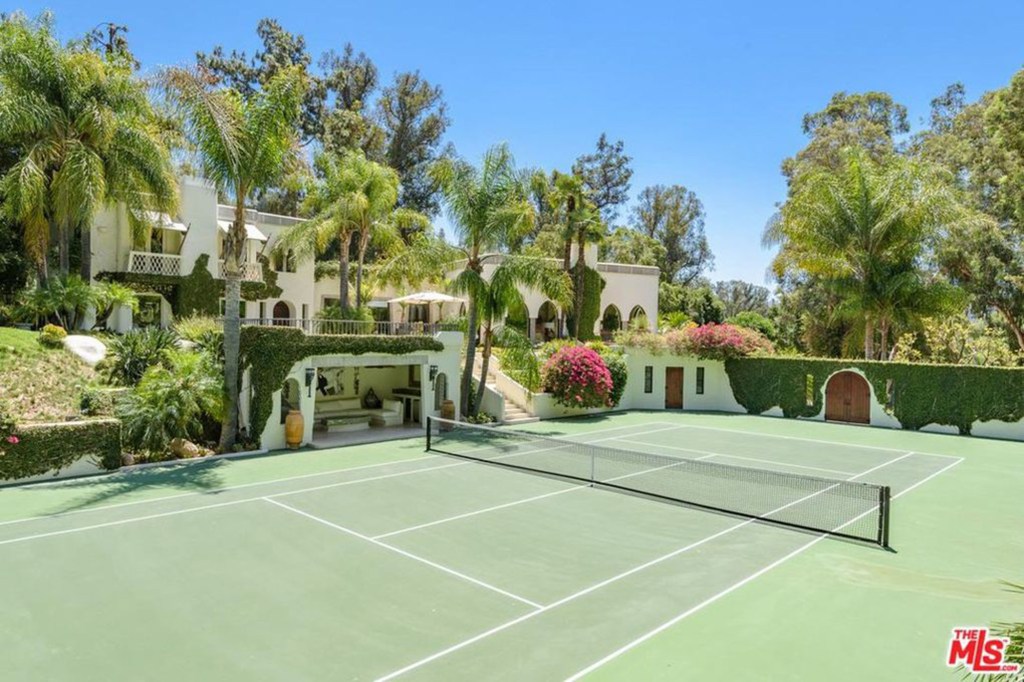 The stylish home has arched windows, ivy-covered terracotta walls, a tennis court and a pool.